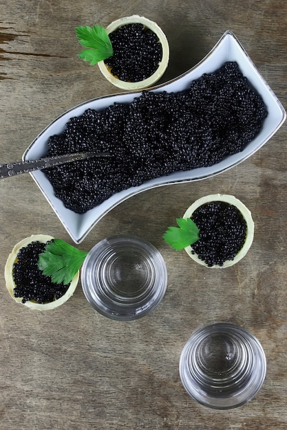 Caviar preto na porção em um fundo de madeira