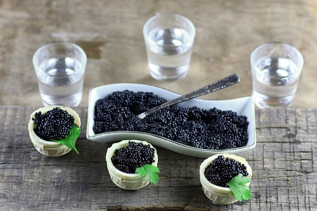 Caviar preto na porção em um fundo de madeira