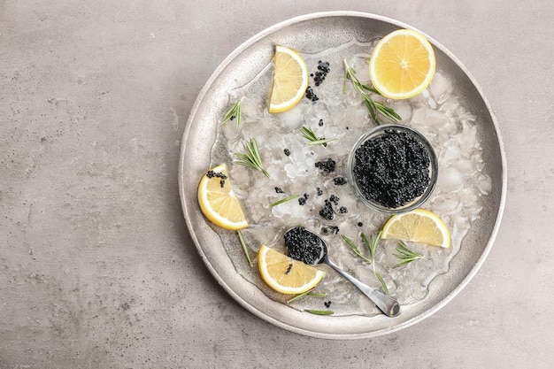 Caviar preto servido com gelo e limão na placa de metal