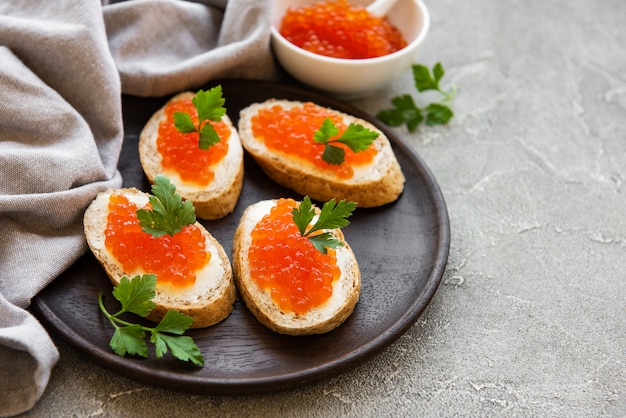 Caviar rojo en bol y sandwiches.