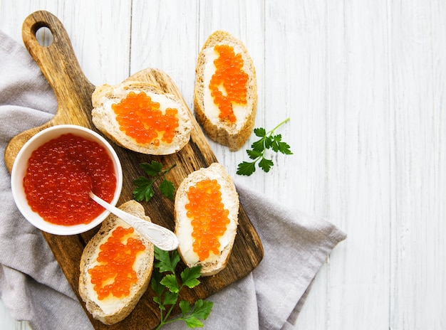 Caviar rojo en bol y sandwiches.