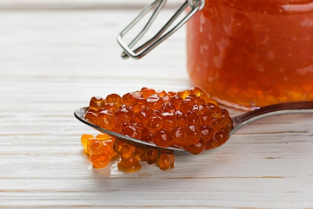 Caviar rojo en cuchara Mariscos de cerca en una mesa de madera blanca Delicadeza de salmón de lujo Vista lateral