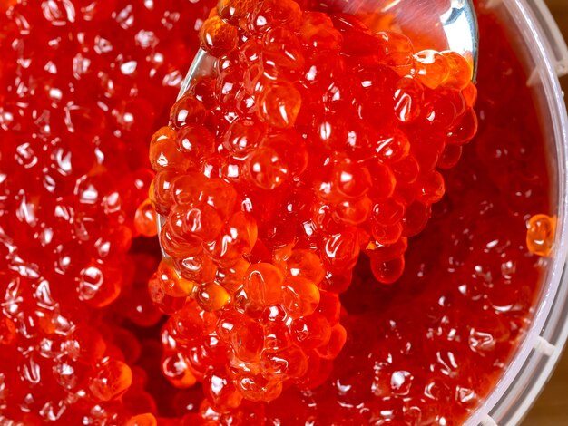 Caviar rojo en una cuchara de metal. manjar gourmet de lujo