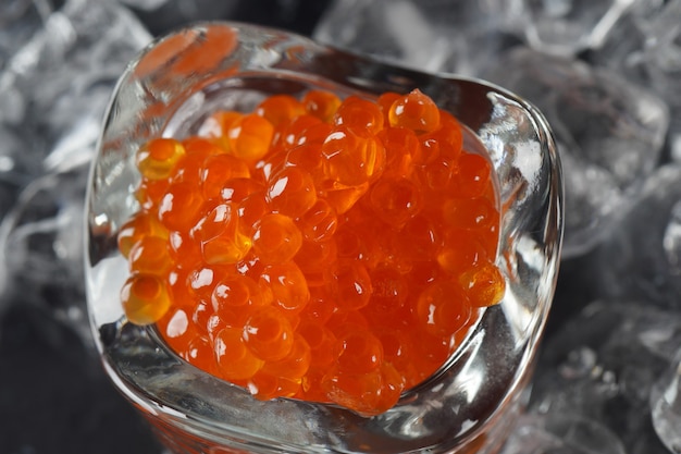 Foto caviar rojo en una cuchara sobre fondo de hielo. caviar de salmón de primer plano. tiendas delicatessen