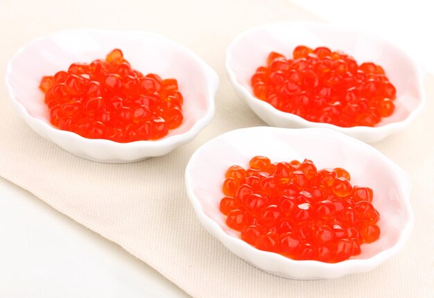 Caviar rojo en cuencos blancos aislados en blanco