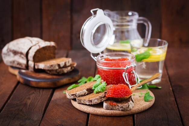 caviar rojo dentro de un frasco de vidrio con rebanadas de pan