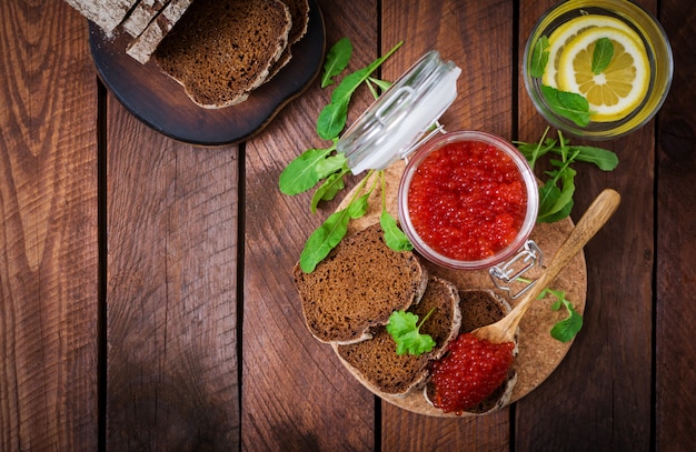 caviar rojo dentro de un frasco de vidrio con rebanadas de pan