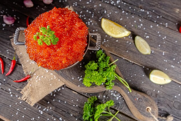 caviar rojo en estilo rústico vintage, un tazón hondo de cubos de cacerola, sobre una tabla de cortar de madera y t