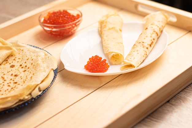 Caviar rojo con grandes panqueques blancos sobre una placa blanca Días de carnaval