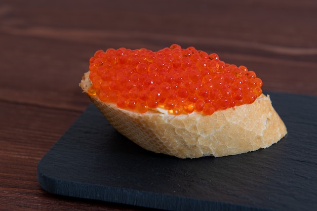 Foto caviar rojo con pan blanco sobre la mesa de madera marrón oscuro