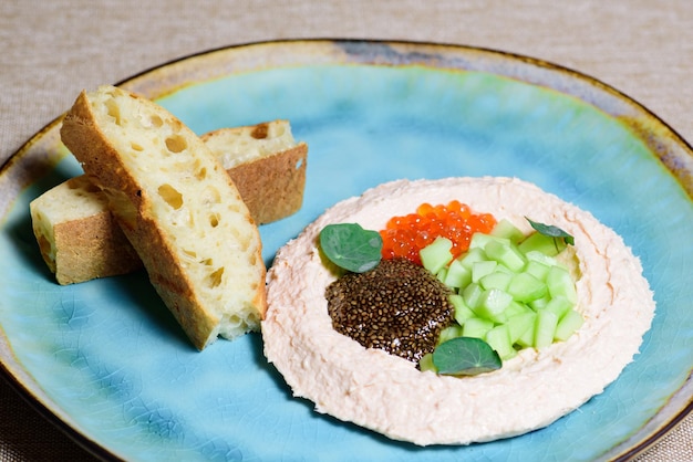 Caviar rojo con puré de patatas y ensalada fresca en un plato azul