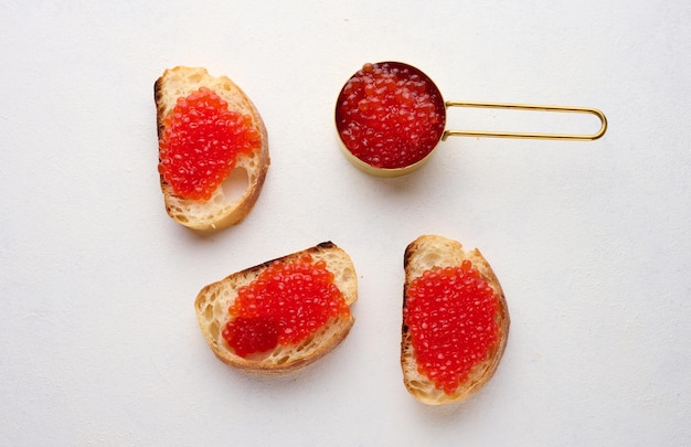 Caviar rojo en rebanadas de pan de trigo blanco en una mesa blanca concepto de cocina de lujo y gourmet