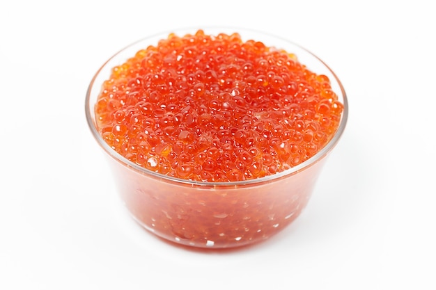 Caviar rojo en recipiente de vidrio aislado en blanco