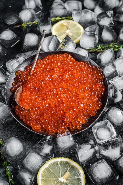 Caviar rojo salado en placa de acero sobre hielo Fondo negro Vista superior