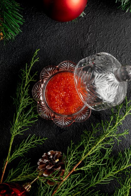 Caviar rojo sobre un fondo oscuro de Navidad decorado con juguetes y ramas