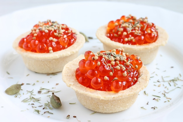 Caviar rojo en tartaletas en plato blanco