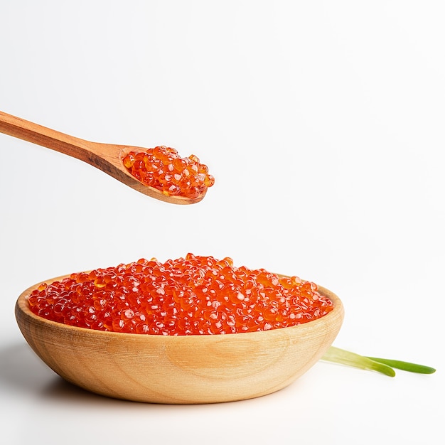 Caviar rojo en una taza de madera sobre un blanco