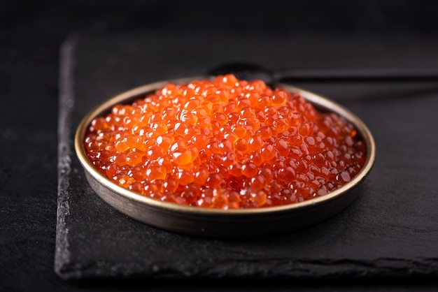 Caviar salgado vermelho grande em uma pequena placa preta