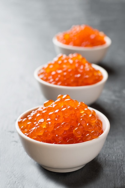 Caviar de salmón rojo en un plato sobre una mesa oscura