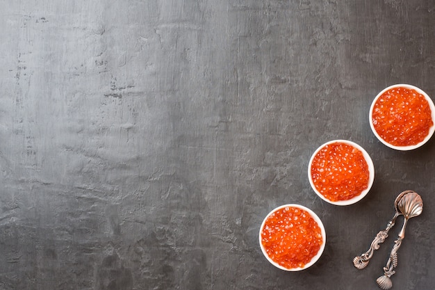 Caviar de los salmones rojos en una placa en una tabla oscura. Copia espacio