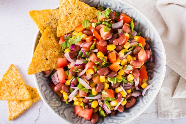 Foto caviar de vaquero de ensalada de verduras mexicanas y nachos en un tazón sobre la mesa vista superior primer plano