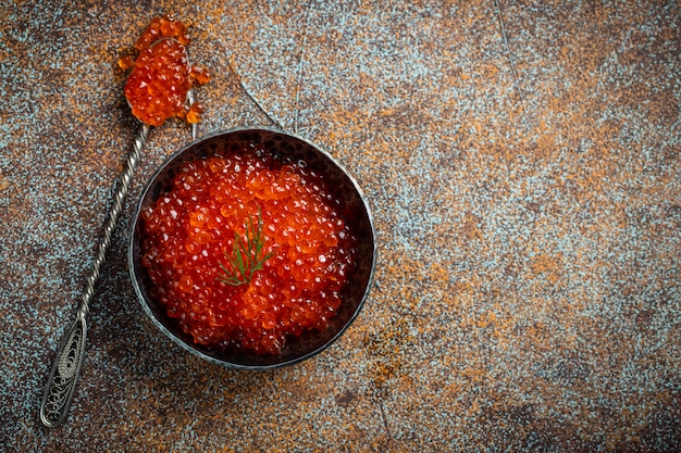 Caviar vermelho delicioso na bacia preta.