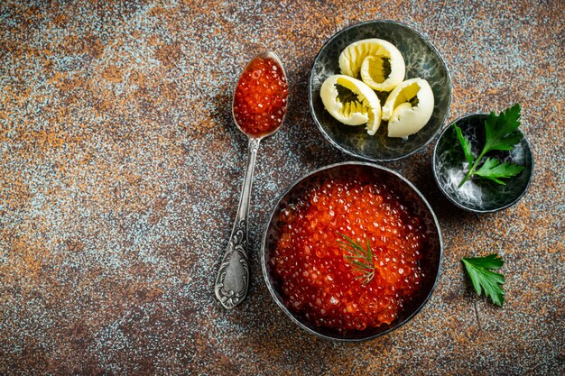 Caviar vermelho delicioso na bacia preta.