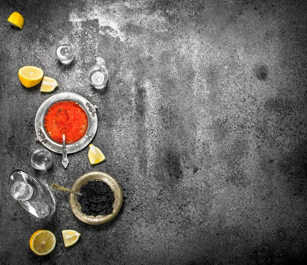 Caviar vermelho e preto com vodka. Sobre fundo rústico.