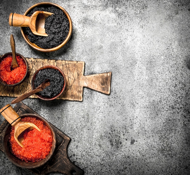 Caviar vermelho e preto em tigelas de madeira.