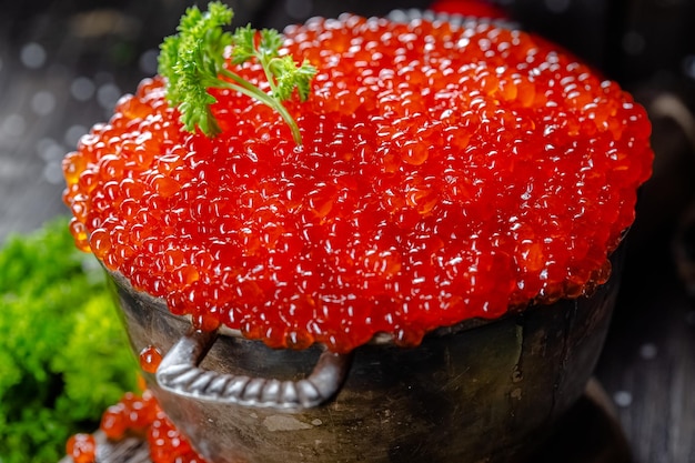 caviar vermelho em estilo vintage rústico, uma tigela funda de panela de baldes, em uma tábua de madeira e t