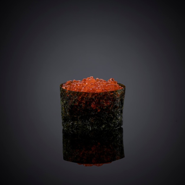 Caviar vermelho em um copo em um fundo cinza-escuro.