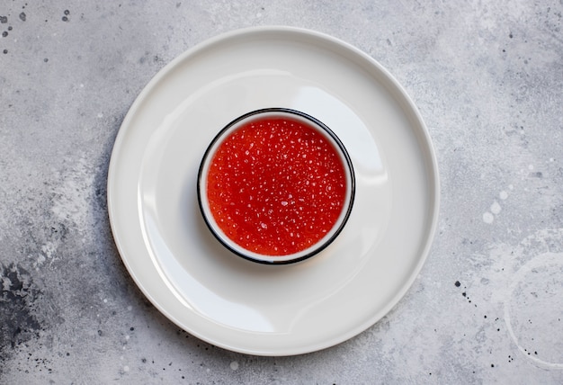 Caviar vermelho em uma tigela branca sobre um fundo claro