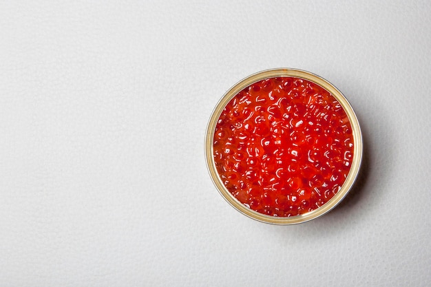 Caviar vermelho na lata aberta em um fundo branco