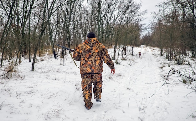 Foto caza de invierno. cazador moviéndose con rifle y buscando presas.