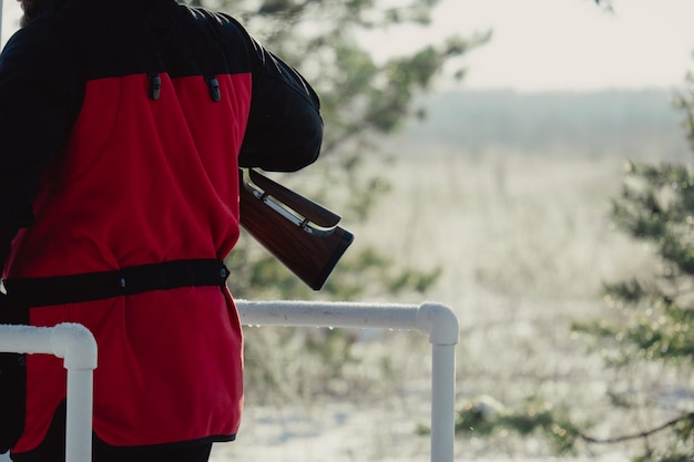 Cazador de camuflaje con rifle en bosque de invierno. Concepto de caza. Hombre asegurando una reserva, en un día de nieve. Hunter apunta con un arma en el bosque nevado