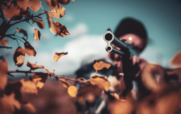 Cazador furtivo con rifle avistando a algunos cazadores de ciervos con escopeta en otoño de caza