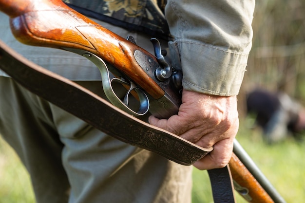 Cazador de hombre maduro con pistola mientras camina en el campo