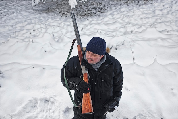 Cazador masculino con su rifle en el bosque en invierno. La caza y el tiro se han practicado durante muchos siglos. Uno de los objetivos es controlar la población animal en la vida silvestre.