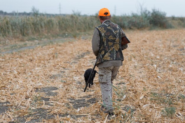 Cazador de patos con escopeta caminando por un prado xARear vista de un hombre con un arma en las manos