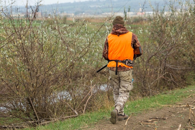 Cazador de patos con escopeta caminando por un prado