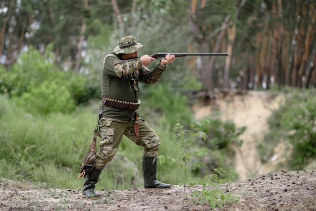 Cazador con pistola en la caza de aves en el bosque de verano.