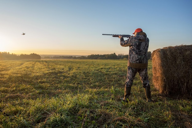 Foto cazador con rifle de escopeta apuntando al faisán