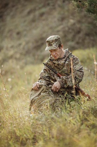 Cazador con ropa de camuflaje listo para cazar con rifle de caza