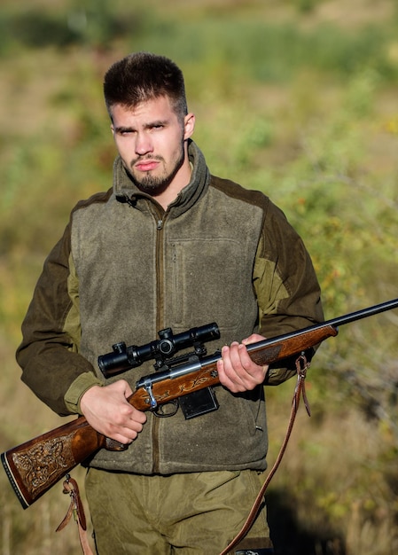 Cazador serio barbudo que pasa tiempo cazando Hombre brutal guardabosques sin afeitar Fondo de naturaleza Permiso de caza Cazador sostiene rifle La caza es un pasatiempo masculino brutal Temporadas de caza y captura