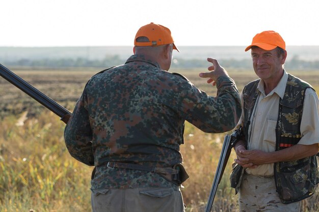 Foto cazadores de patos con escopeta caminando por un prado