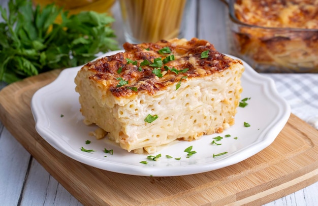 Cazuela de pasta con salsa bechamel cubierta con queso mozzarella derretido y servida en una fuente para horno blanca sobre una mesa (nombre turco; firinda makarna o firin makarna)