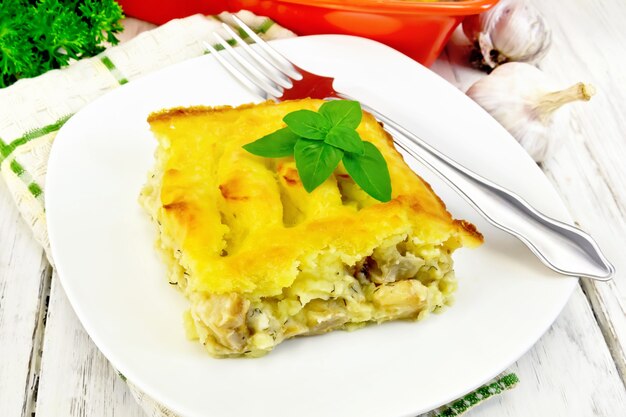 Cazuela de puré de patatas con filete de pescado en un plato sobre una toalla contra una tabla de madera clara