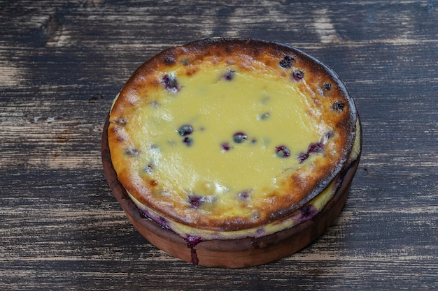 Cazuela de requesón dulce con grosella negra y sémola sobre mesa de madera Cuenco de cerámica con cazuela de requesón al horno