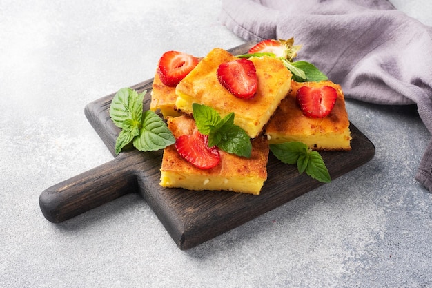 Cazuela de requesón con fresas y menta delicioso postre casero hecho de cuajada y bayas frescas con crema espacio de copia de fondo de hormigón gris