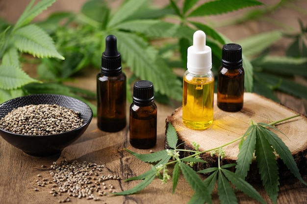 CBD-Hanföl in Flaschen und Hanfsamen mit Cannabisblatt auf Holzhintergrund Hanf-Kräuter-Alternativmedizin